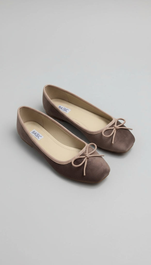 Pair of brown flats with bow details on a concrete floor