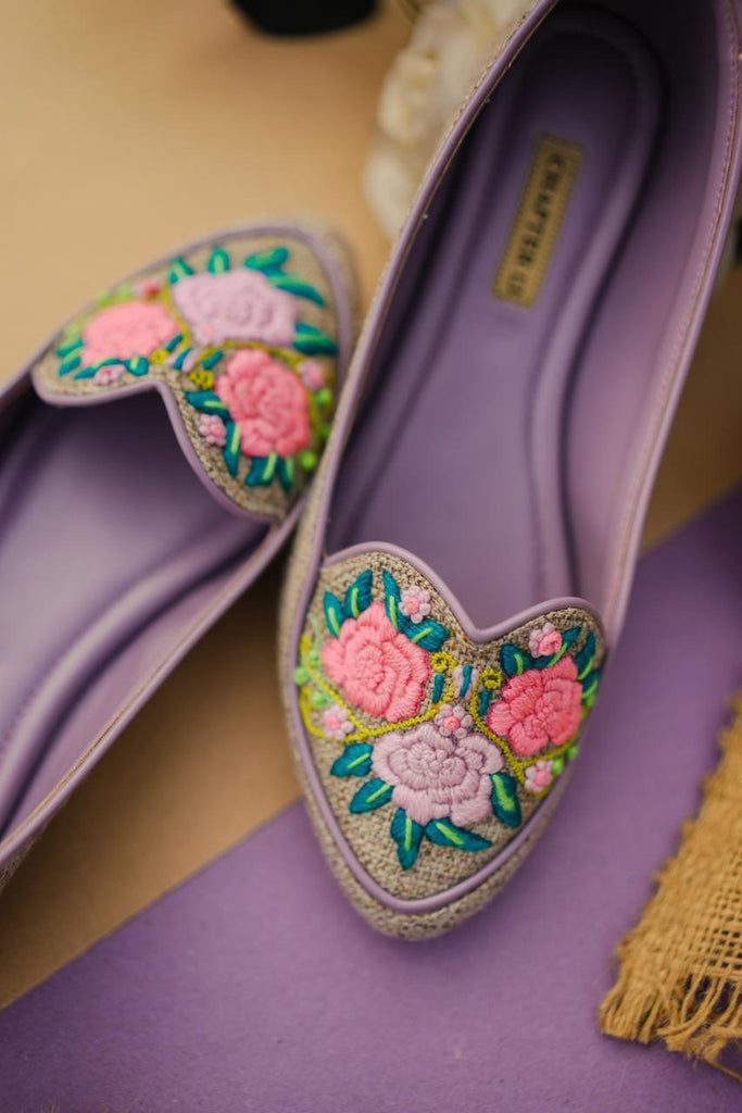 Purple flats with floral embroidery on a purple surface
