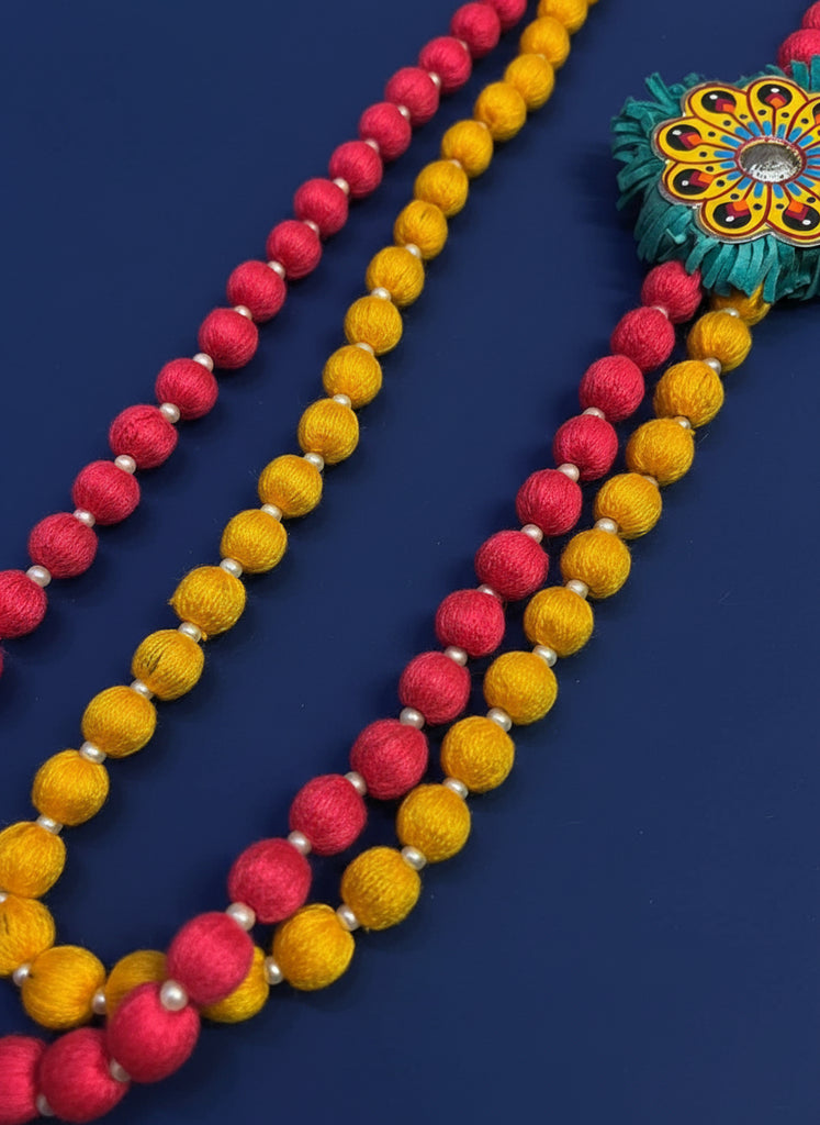Colorful beaded necklace with red and yellow beads on a wooden surface