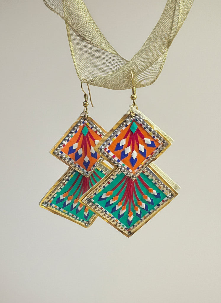 Colorful geometric earrings on a blue background with gold text