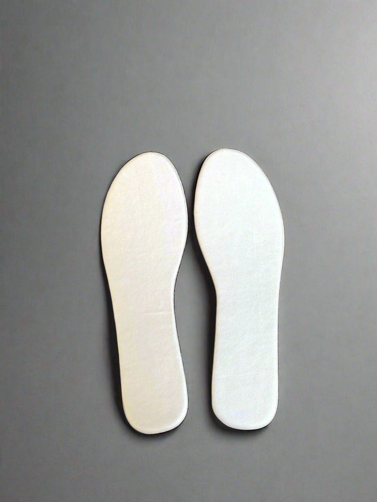 Pair of white shoe insoles on a gray background